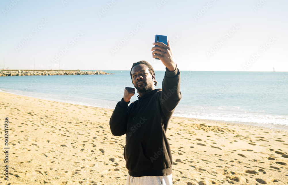 Afro man with dreadlocks takes a selfie while training and doing sports on the beach. Personal motivation Afro man with dreadlocks takes a selfie while training and doing sports on the beach. Personal motivation