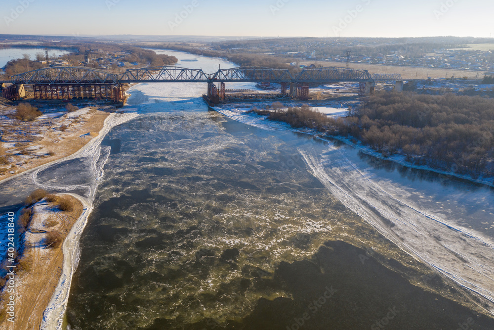 Aerial view of railway bridge over frozen Oka river at sunny winter day. Serpukhov, Moscow Oblast, Russia.