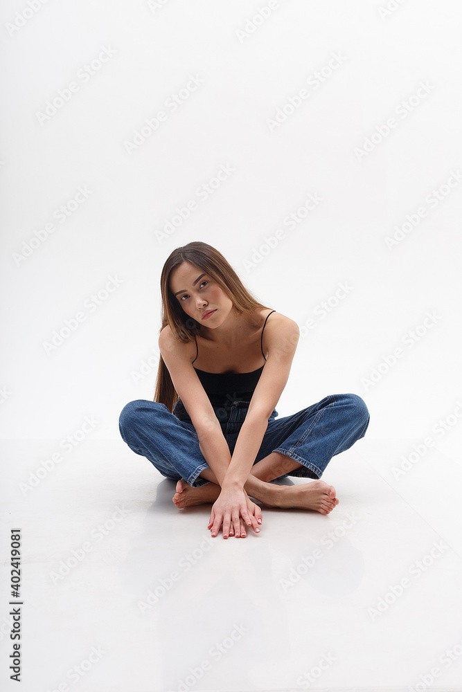 young attractive asian woman with long hair in black top, blue jeans isolated on white studio background. skinny pretty female sitting on cyclorama with legs crossed. model tests of beautiful lady young attractive asian woman with long hair in black top, blue jeans isolated on white studio background. skinny pretty female sitting on cyclorama with legs crossed. model tests of beautiful lady