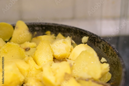 Fried potatoes. Cast-iron pan. Wooden spatula. Homemade food.