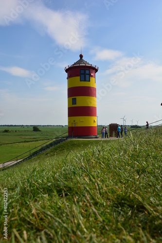 Leuchtturm Pilsum mit blauen Himmel und Gras auf den Nordseedeich in Krummh  rn in Ostfriesland  Niedersachsen  Deutschland