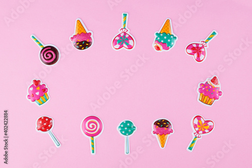 Layout of various candy stickers on pastel pink background with copy space.