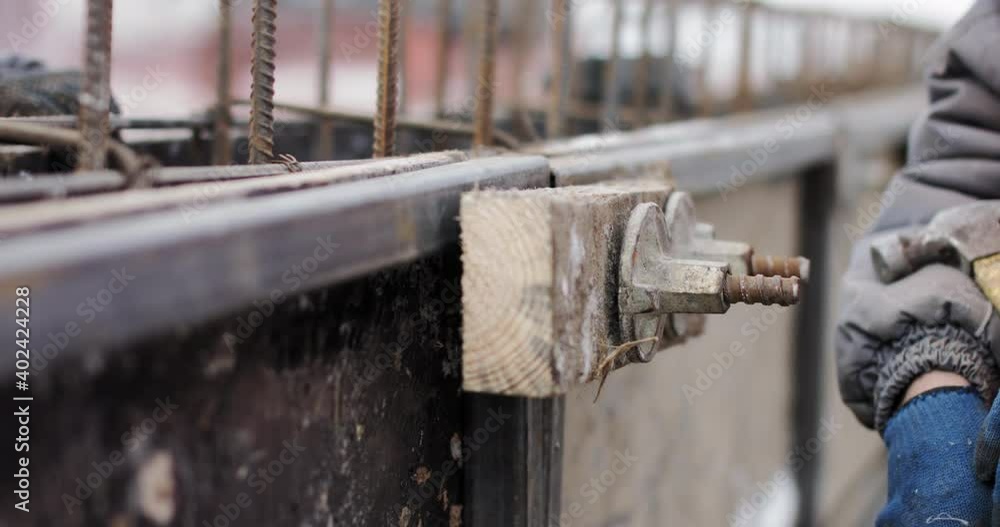 Engineers work with metal constructions while building a house. The worker fixes the form for pouring concrete, aligns metal boards. Filling the foundation of the building. The hammer fixes the form Engineers work with metal constructions while building a house. The worker fixes the form for pouring concrete, aligns metal boards. Filling the foundation of the building. The hammer fixes the form
