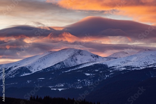 Sunset over snowy peaks in Rila Mountain  Bulgaria. Attractive orange cloudy sky  white slopes  natural landscape panoramic view. Perfect winter conditions for travel  sport recreation and tourism.