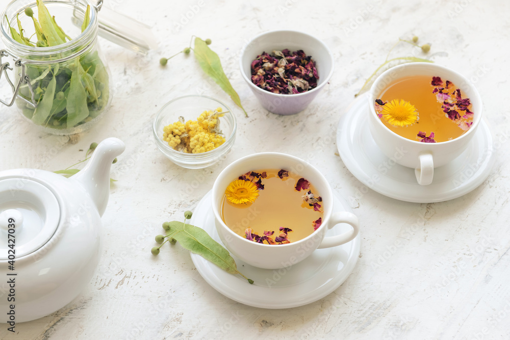 Herbs, teapot and cups with floral tea on light background Herbs, teapot and cups with floral tea on light background