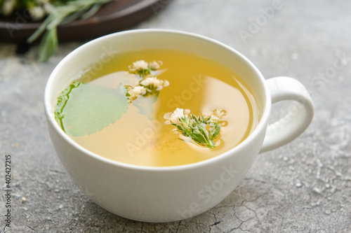 Cup with herbal tea on gray background