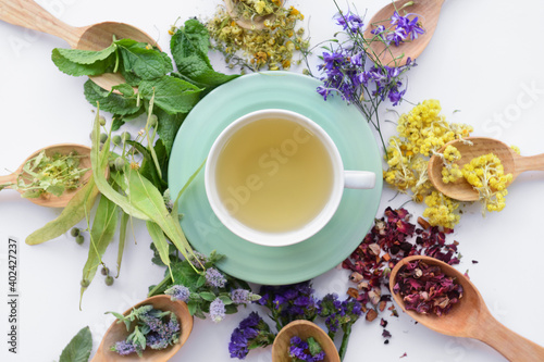 Dry flowers, spoons and cup with floral tea on light background