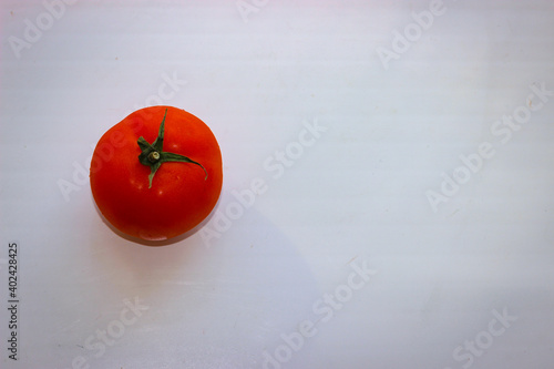 One tomato on a white surface