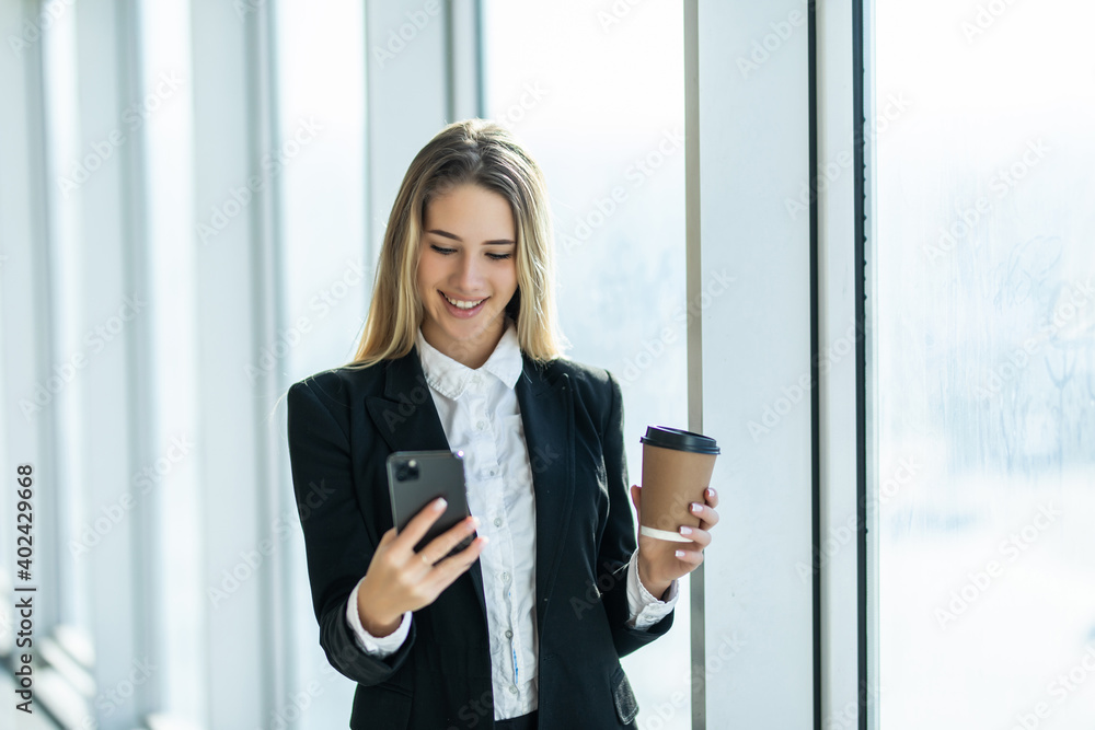 Young business woman with coffee and use on the phone near office