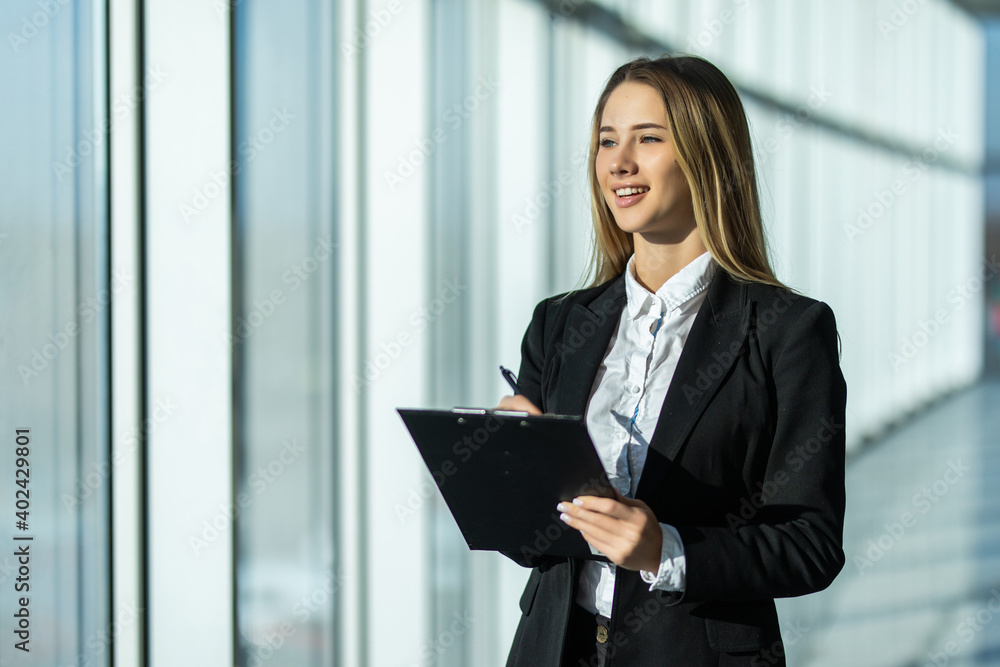 Portrait of young business woman with clipboard making notes in the office Portrait of young business woman with clipboard making notes in the office