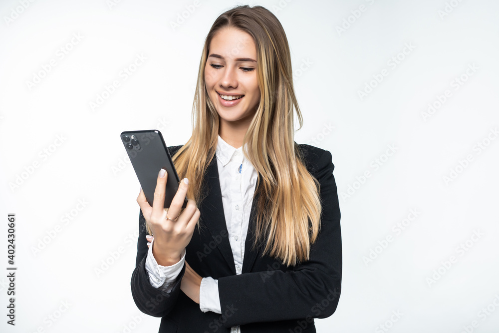 Portrait of surprised and impressed business woman with widened eyes and opened mouth, stunned on phone while standing against white background. Girl uses some app Portrait of surprised and impressed business woman with widened eyes and opened mouth, stunned on phone while standing against white background. Girl uses some app