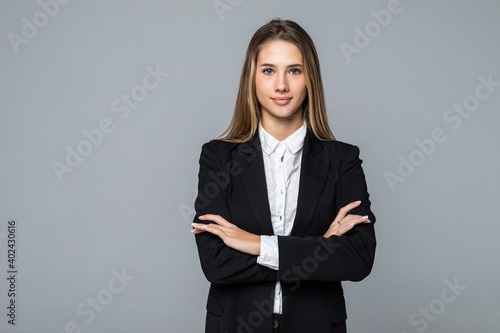 Smiling business woman with crossed arms standing against a white background.