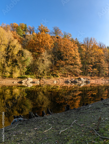 rocks and trees in autumn colors reflection in water of river