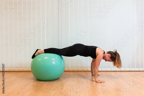 girl pilates trainer does plank fitball basic posture in fitness center