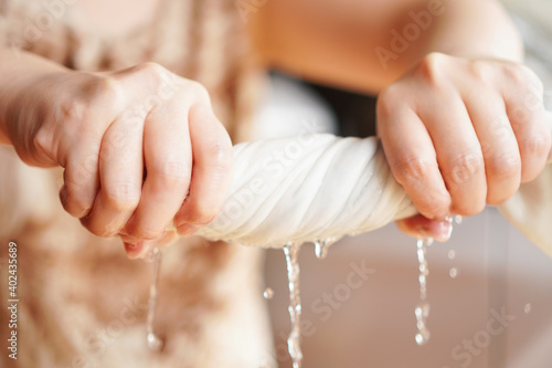 Two woman hands wring wet cloth after washing by twist and squeeze. Housework ,laundry and optimization concept ,selective focus on hand on the left photo