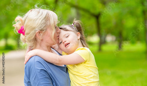 Happy family. Mom and her little daughter with syndrom down have a fun in summer park. Empty space for text