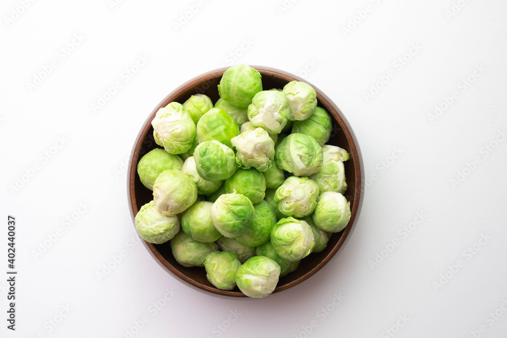 green Brussels sprouts its leaves lie on the table and in a wooden bowl green Brussels sprouts its leaves lie on the table and in a wooden bowl