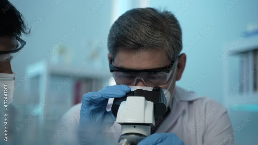 a scientist researching and analyzing results in the laboratory, holding and looking at a test tube while testing samples for the presence of coronavirus (COVID-19), applying the vaccine a scientist researching and analyzing results in the laboratory, holding and looking at a test tube while testing samples for the presence of coronavirus (COVID-19), applying the vaccine