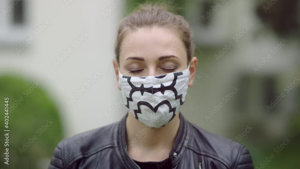 Face of a mid-thirties female wearing a mask. She's opening her eyes which were closed. Face of a mid-thirties female wearing a mask. She's opening her eyes which were closed.
