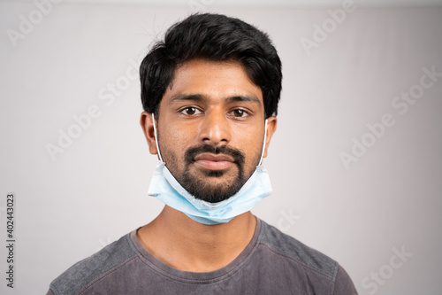 фотографія young man wearing medical mask on neck- concept showing of improper way of using face masks during coronavirus or covid-19 crisis