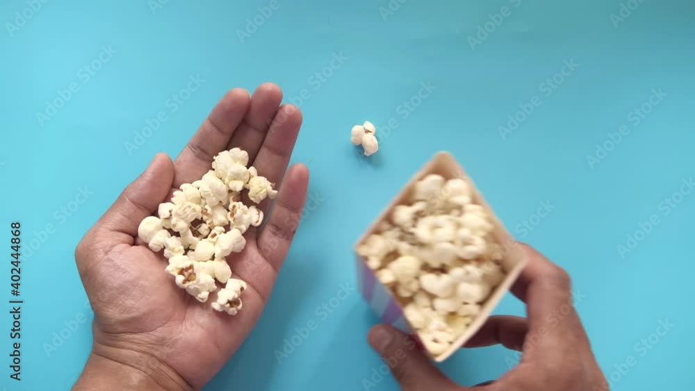 top view of man eating popcorn on blue background top view of man eating popcorn on blue background