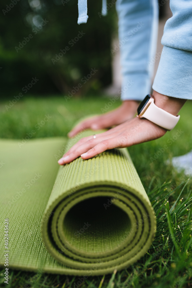 Close-up of woman folding roll fitness after working out in the park Close-up of woman folding roll fitness after working out in the park