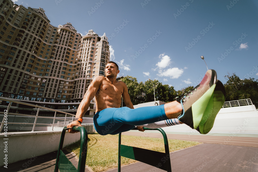 Strong man doing exercises on uneven bars in outdoor street gym. Stock
