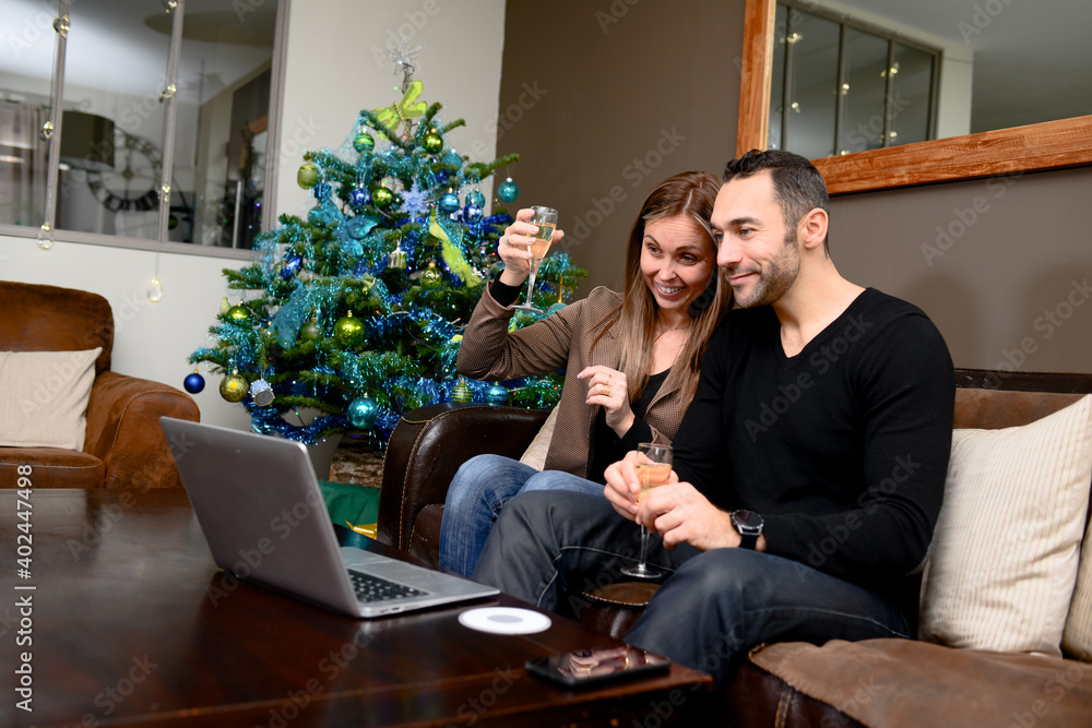 happy young couple remotely calling friends during lockdown christmas with laptop computer happy young couple remotely calling friends during lockdown christmas with laptop computer