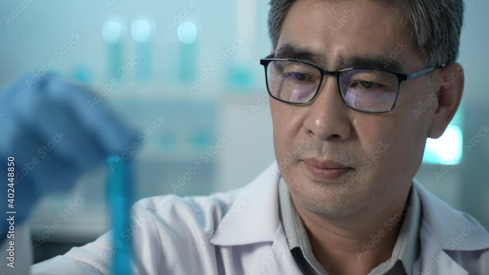 a scientist researching and analyzing results in the laboratory, holding and looking at a test tube while testing samples for the presence of coronavirus (COVID-19), applying the vaccine a scientist researching and analyzing results in the laboratory, holding and looking at a test tube while testing samples for the presence of coronavirus (COVID-19), applying the vaccine