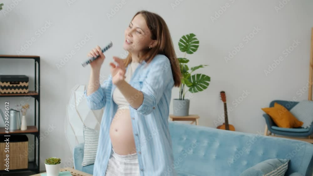 Portrait of joyful pregnant mother dancing and singing enjoying music having fun alone in apartment. Youth lifestyle and healthy pregnancy concept. Portrait of joyful pregnant mother dancing and singing enjoying music having fun alone in apartment. Youth lifestyle and healthy pregnancy concept.