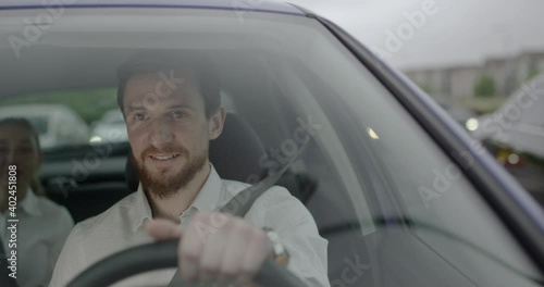 Handsome Male taxi driver smiles and talks to his passenger inside the car