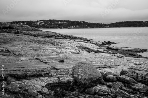 Smooth rocks and large boulder on a shoreline in a monochrome photograph