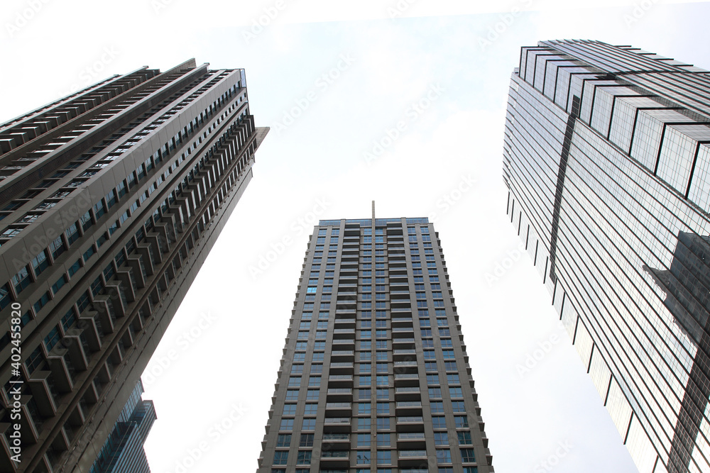 Low angle view of three skyscrapers with bright sky on the background