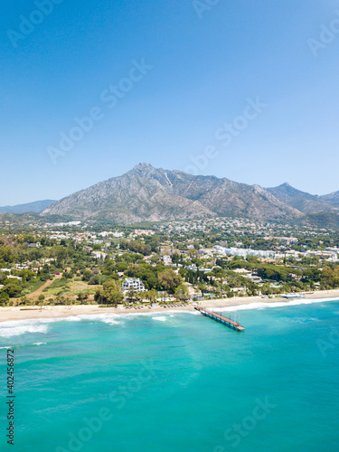 Unique aerial view of luxury and exclusive area in Marbella, golden mile beach, view of Puente Romano Bridge and in background famous La Concha mountain. Emerald water colour 