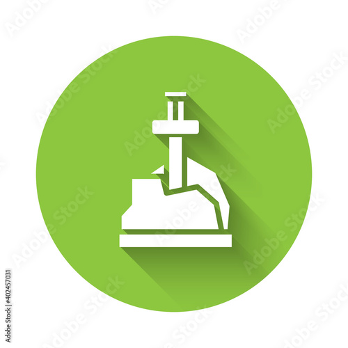 White Sword in the stone icon isolated with long shadow. Excalibur the sword in the stone from the Arthurian legends. Green circle button. Vector.