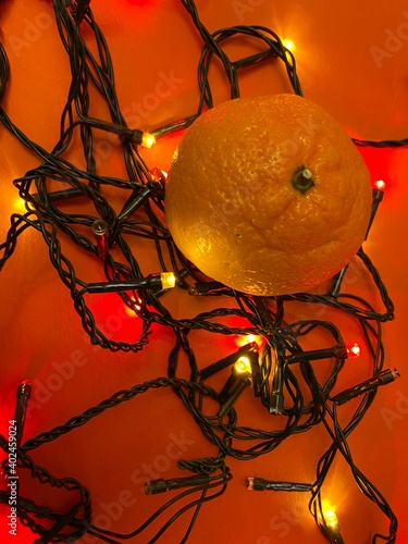 Fesitve Christmas background with garland lights and tangerine. New Year colorful abstract backdrop