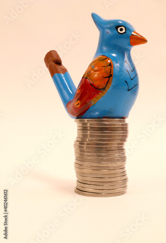 A blue bird with a large pile of old Swedish silver coins. Concept of wealth. Close up and isolated on a white background. Stockholm, Sweden. photo