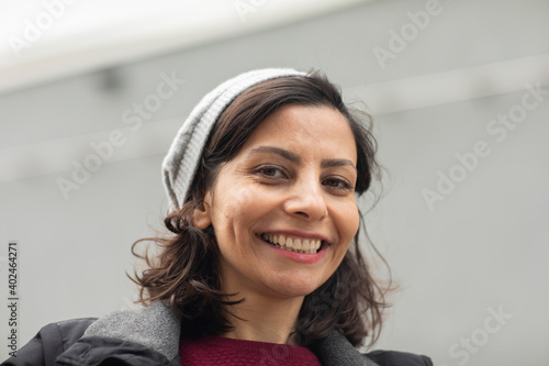 Frau  mit offenen dunklen Haaren  und Mütze außen  und lachend photo