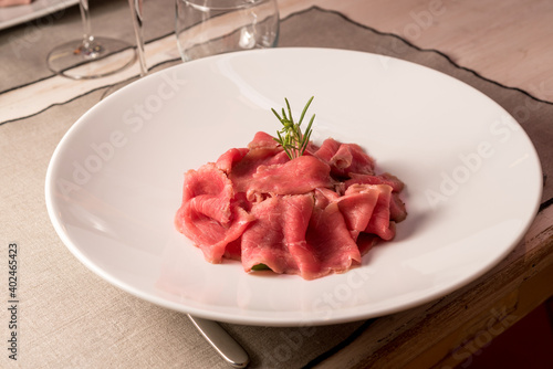 Beef carpaccio with rosemary on a table in a typical trattoria