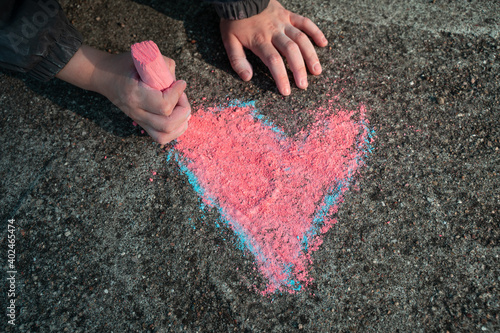 Das Kind malt mit der Kreide ein Herz auf der Strasse