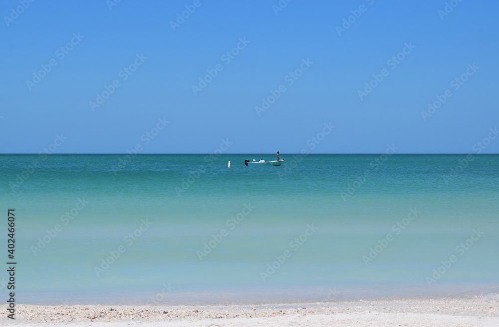 Blue green ocean from sand with boat and blue sky