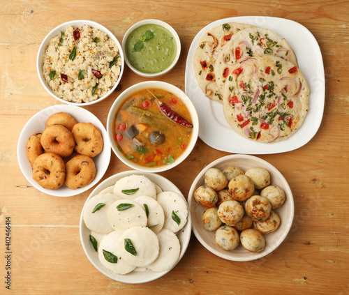 Group of South Indian food like Masala Dosa, Uttapam, Idli/idly, Wada/vada, sambar, appam, semolina halwa, upma served over banana leaf with colourful chutneys,  photo