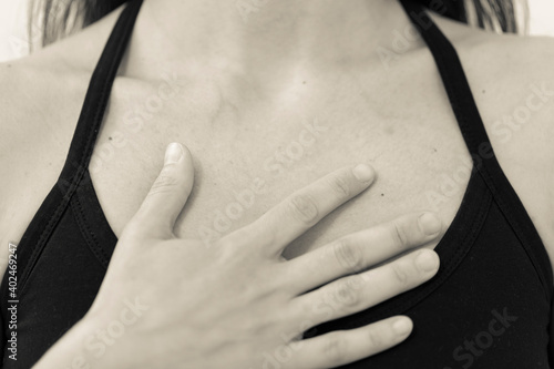 Canvas Print BW horizontal detail of chest and shoulders of yogini wearing black one strap yoga top, with open hand placed on the heart area