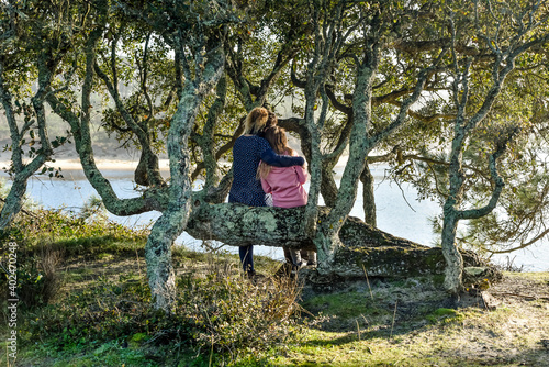 young girl and her mother hugging in front of a lake photo