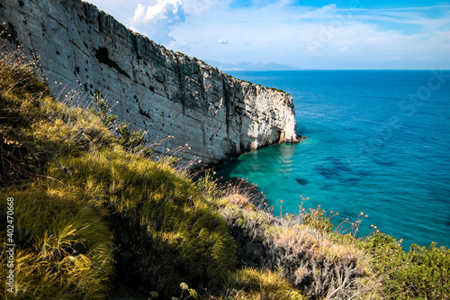 view of the coast on the Greek island of Zakynthos. The sea is clear blue and the sky blue with white clouds.