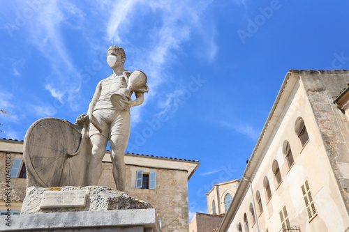 Ancient statue with face mask in front of blue sky at Spanish market in Sineu, Mallorca, Spain photo