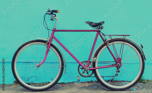 Retro pink bicycle standing in the city on a blue background