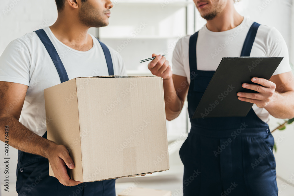 cropped view of multicultural movers holding boxes in apartment cropped view of multicultural movers holding boxes in apartment