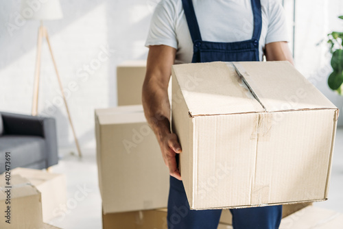 partial view of mover in uniform holding carton box in apartment © LIGHTFIELD STUDIOS
