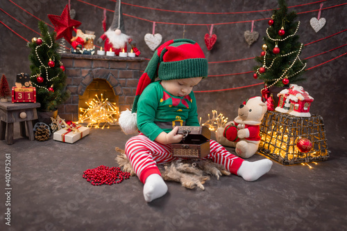 beautiful baby, boy, against the background of a fireplace in Santa's house, dressed as a gnome, lights, Christmas tree, holiday, joy
